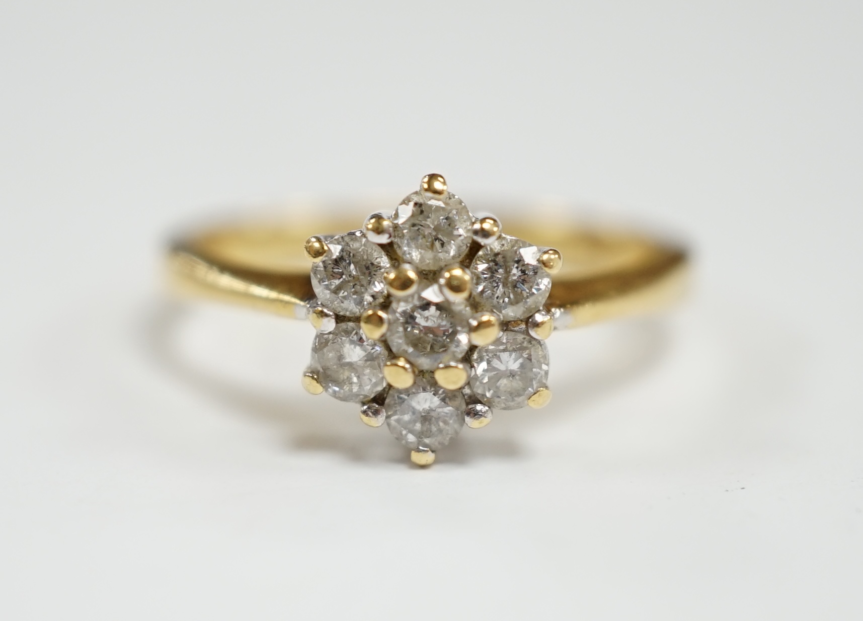 A modern 18ct gold and seven stone diamond cluster set flower head ring, size N, gross weight 3.6 grams.